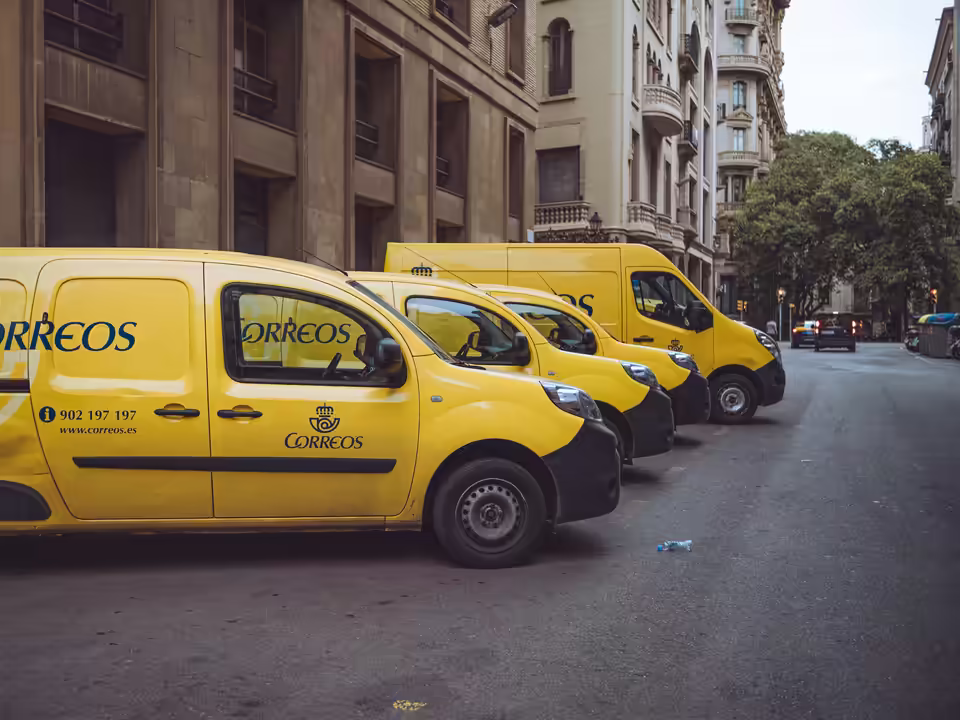 A row of yellow Correos delivery vans parked along a city street